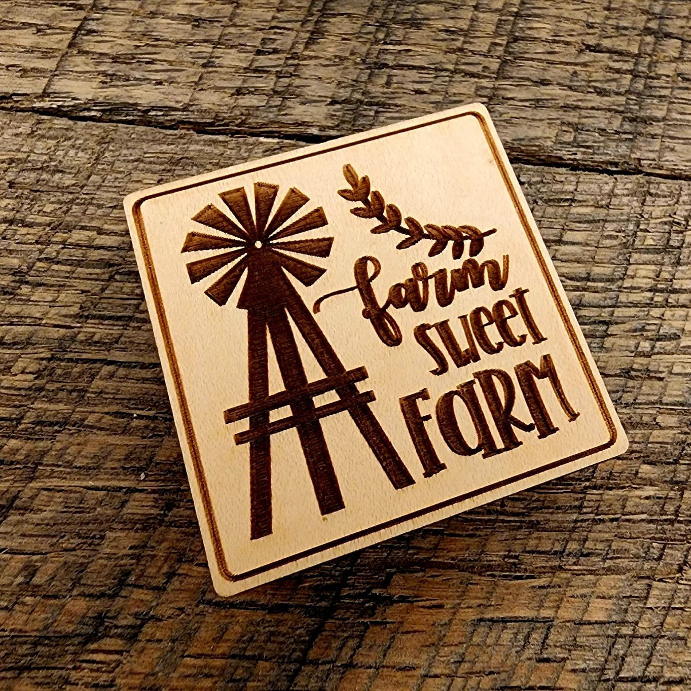 Magnet with "Farm Sweet Farm" printed on it. A windmill design to the left of the lettering and the magnet is tilted left