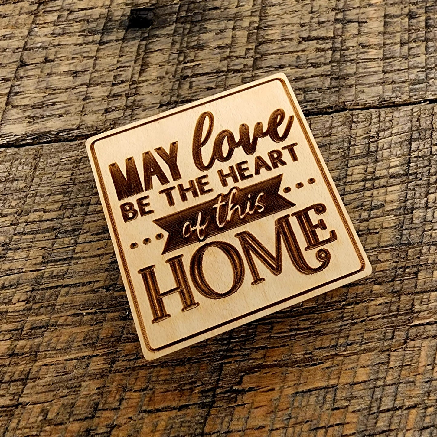 Magnet saying "May Love Be The Heart of this Home" tilted to the left