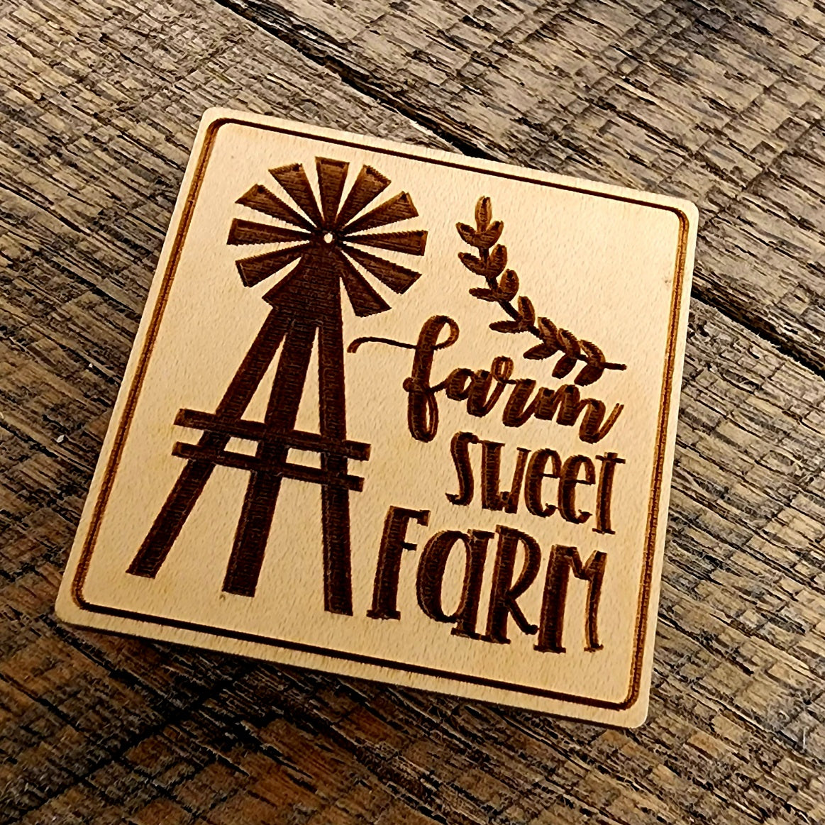Magnet with "Farm Sweet Farm" printed on it. A windmill design to the left of the lettering and the magnet is tilted right