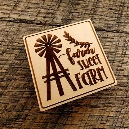 Magnet with "Farm Sweet Farm" printed on it. A windmill design to the left of the lettering and the magnet is tilted left