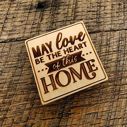 Magnet saying "May Love Be The Heart of this Home" tilted to the left