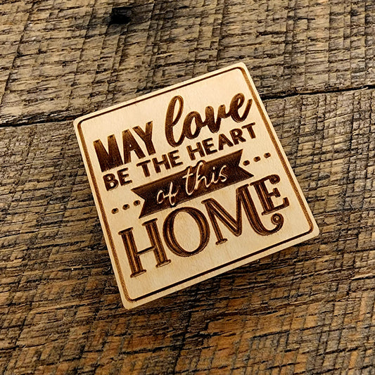 Magnet saying "May Love Be The Heart of this Home" tilted to the left